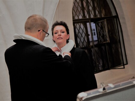 Billede af mandlig præst, der giver kvindelig præst præstekrave på